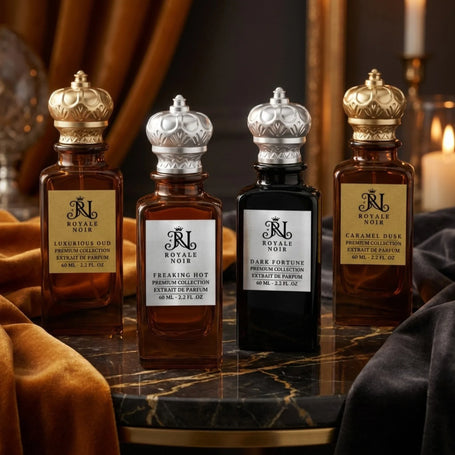 Royale Noir premium perfume collection displayed in elegant amber and black glass bottles with gold and silver crown caps on a marble table