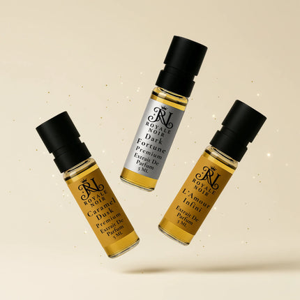Three royale noir perfume tester bottles with black caps and gold labels on a beige background.