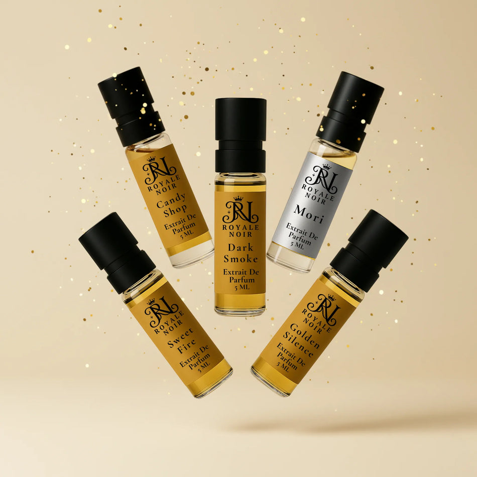 Five royale noir perfume tester bottles with black caps and gold labels on a beige background.