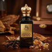 Perfume bottle labeled 'Royale Noir' with gold cap on a wooden surface with dried leaves and vanilla beans.