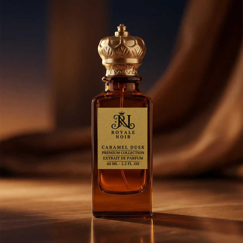 Perfume bottle labeled 'Royale Noir caramel dusk' with a gold cap on a reflective surface.